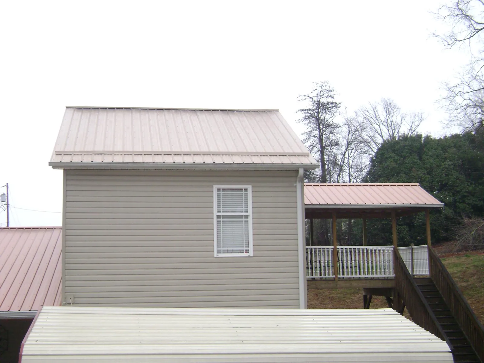 Tan metal roofs on a two story addition and attached porch, from a Roof Replacement job in Williamsport